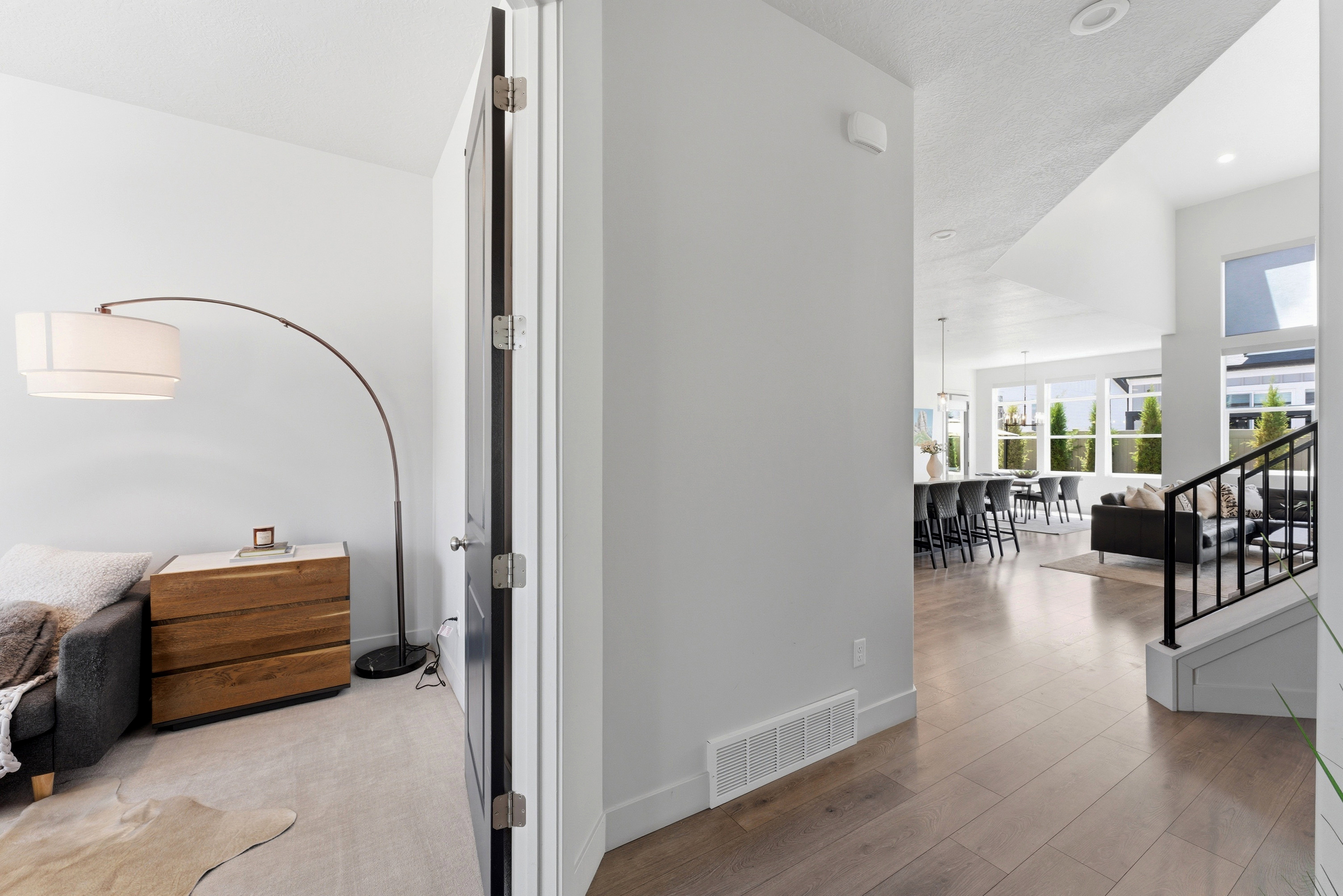 Open-concept living area with abundant natural light, featuring LVP-finish flooring and a black metal staircase railing