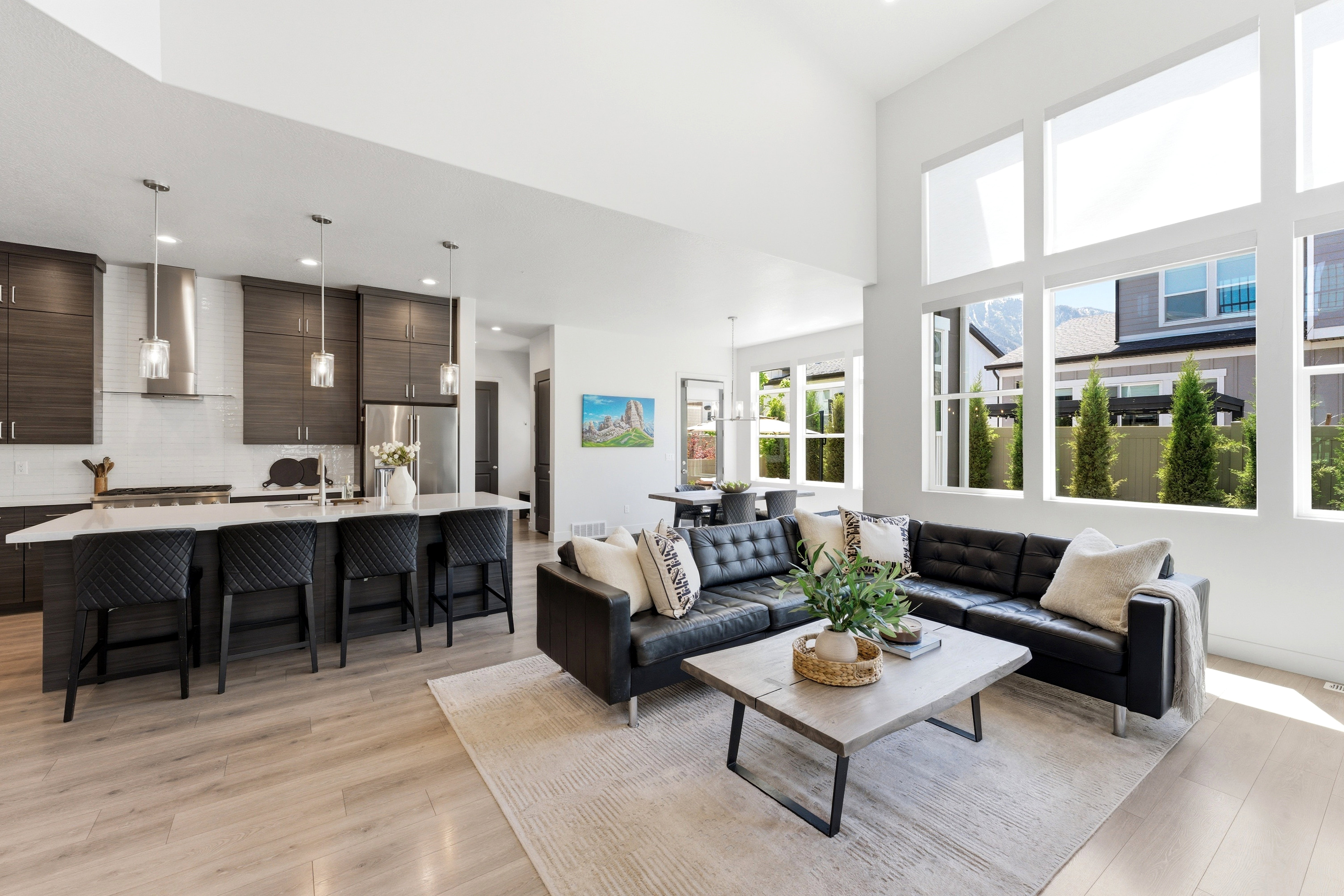 Open-concept living space featuring high ceilings, light LVP-finish flooring, and abundant natural light from large windows