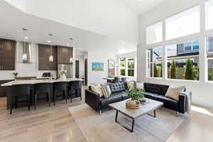 Open-concept living space featuring high ceilings, light LVP-finish flooring, and abundant natural light from large windows