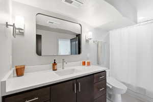 Bathroom featuring a dark wood-finish vanity with an integrated sink and white countertop, complemented by a rectangular frameless mirror and modern wall sconces