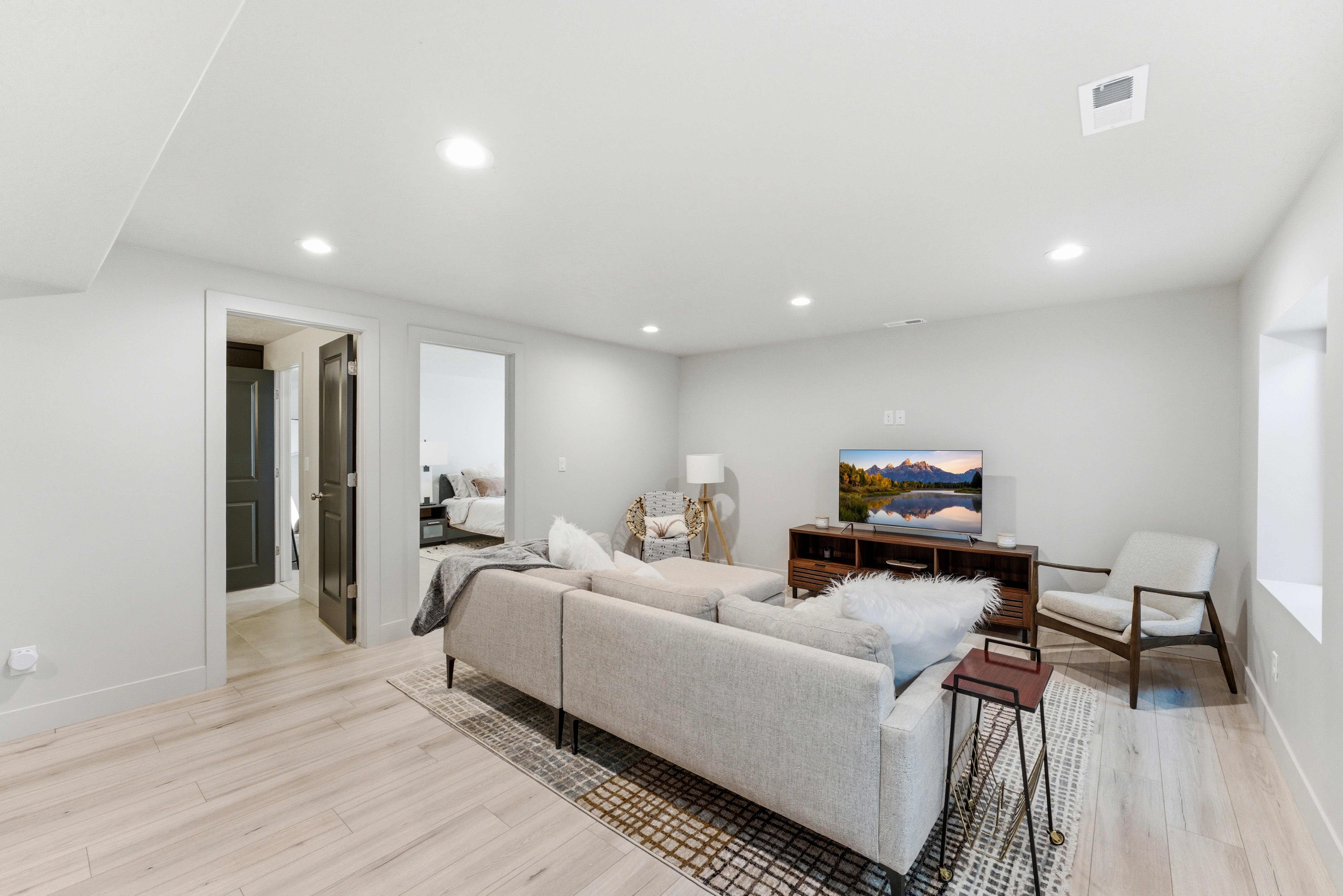 Spacious living area featuring light LVP-finish flooring, recessed lighting, and crisp white walls