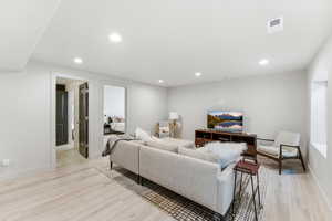 Spacious living area featuring light LVP-finish flooring, recessed lighting, and crisp white walls