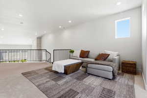 Carpeted loft area featuring a window, recessed lighting, and black metal railings