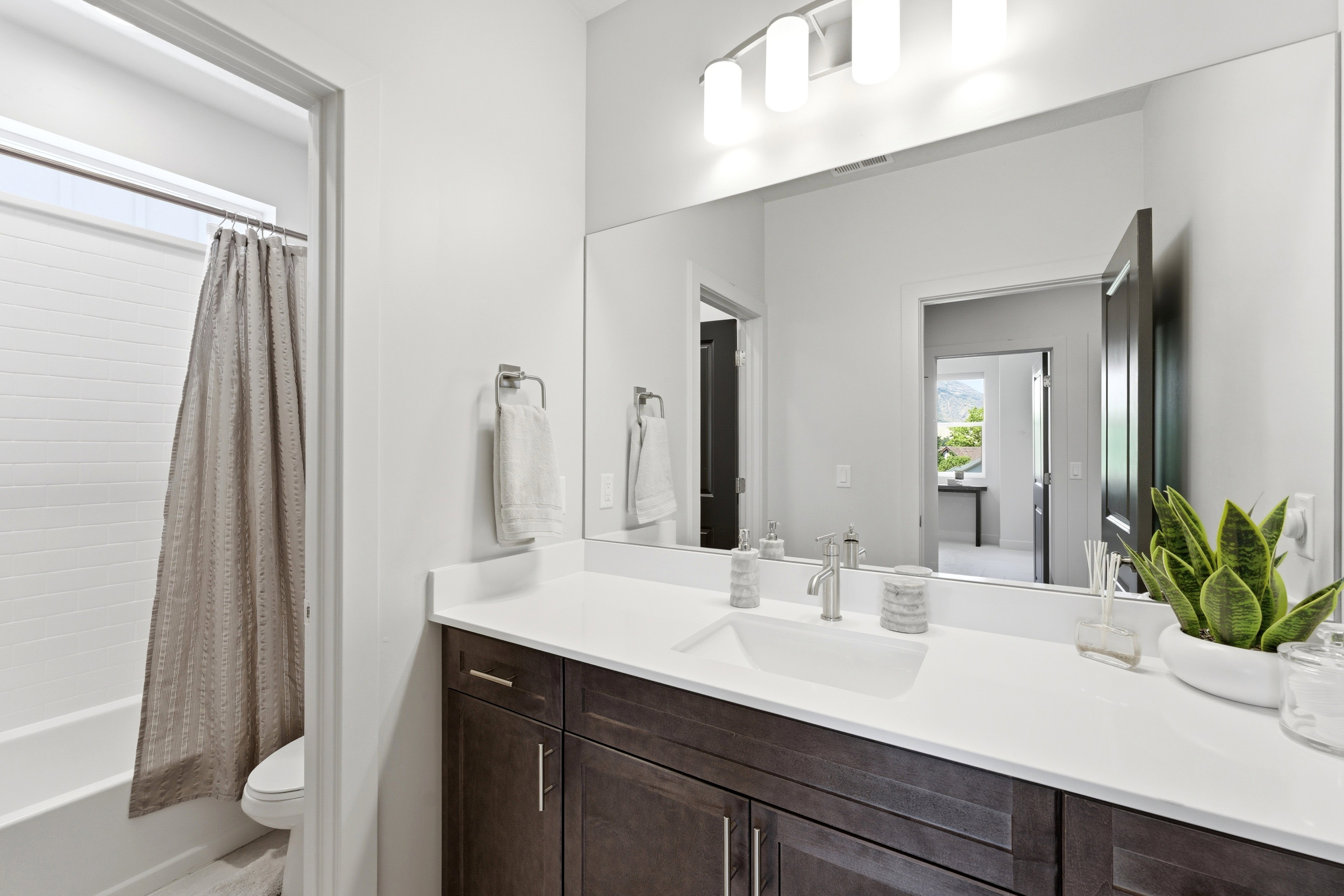 Bathroom featuring a dark wood vanity with a white countertop and integrated sink, brushed nickel faucet, and a large mirror
