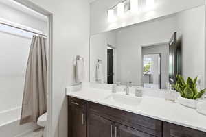 Bathroom featuring a dark wood vanity with a white countertop and integrated sink, brushed nickel faucet, and a large mirror