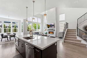 Open-concept living space featuring a modern kitchen island with an undermount sink, stainless steel dishwasher, and microwave drawer
