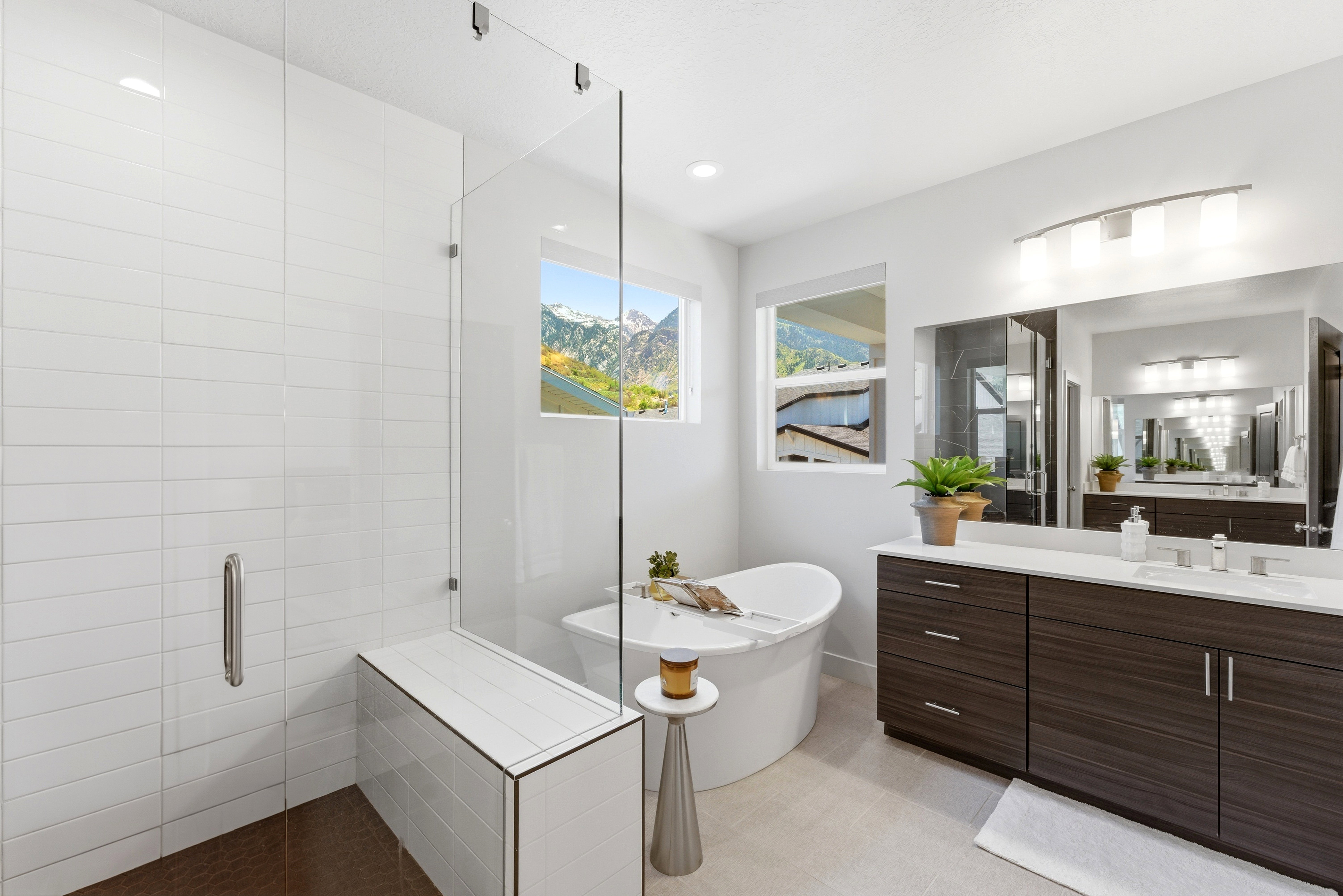 Spacious bathroom featuring a freestanding soaking tub, a large glass-enclosed shower with a built-in bench, a double vanity with ample storage, and two large windows