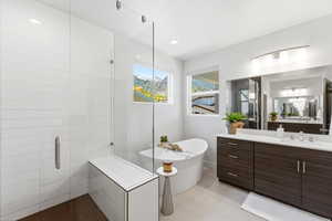 Spacious bathroom featuring a freestanding soaking tub, a large glass-enclosed shower with a built-in bench, a double vanity with ample storage, and two large windows