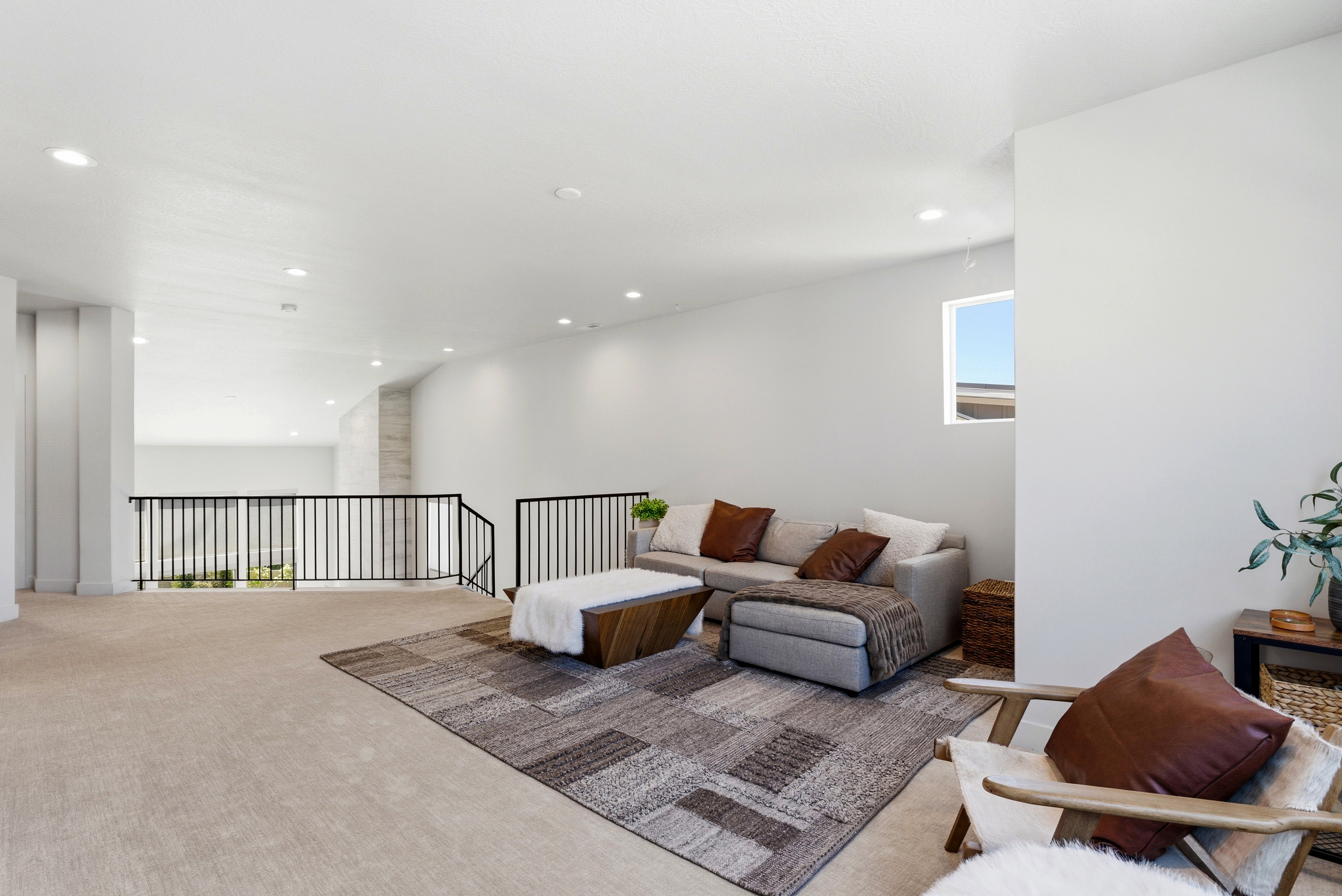 Open loft space featuring light-colored carpeting throughout, white walls, and recessed lighting
