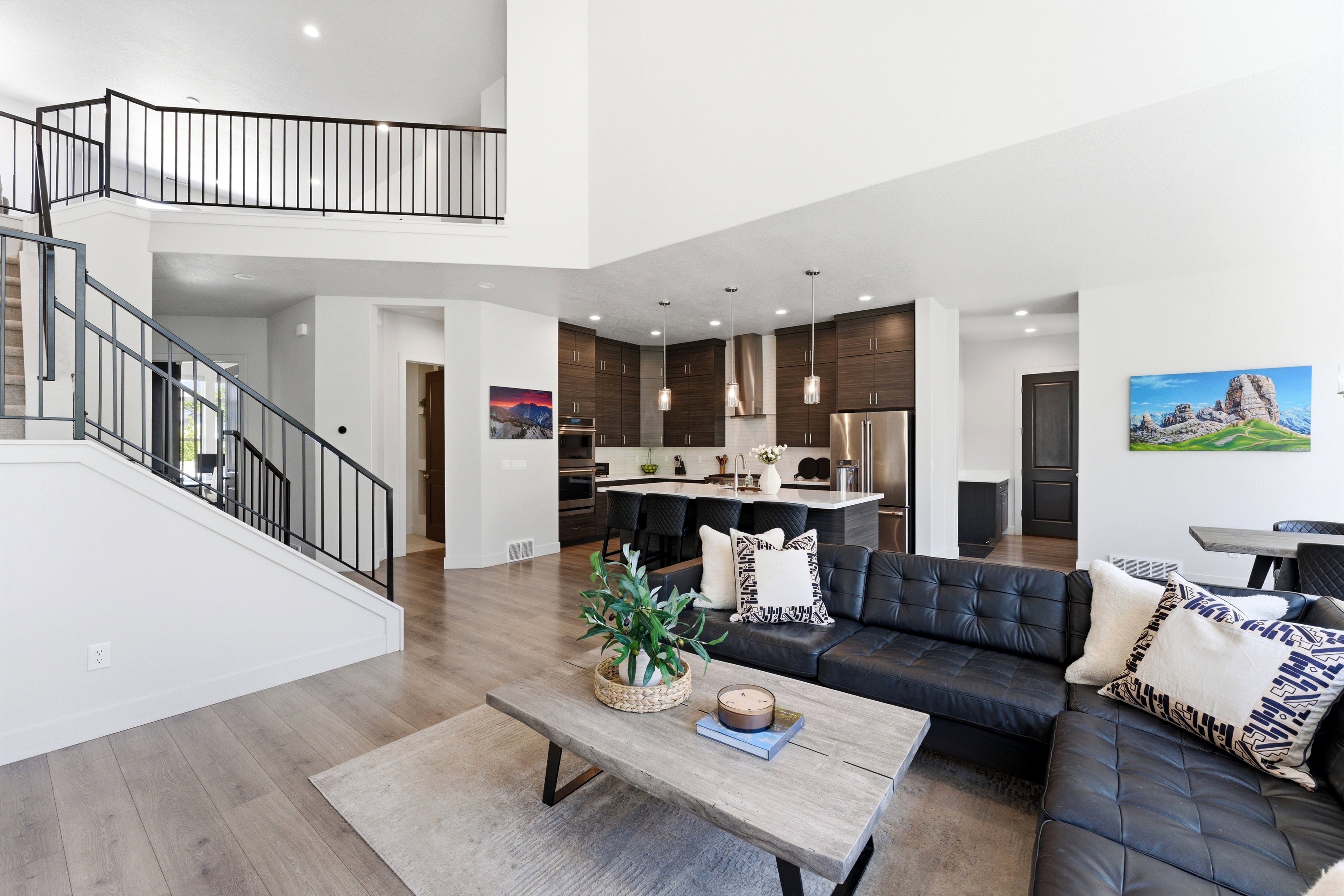 Spacious living area featuring high ceilings, LVP-finish flooring, and a contemporary open staircase with black metal railings