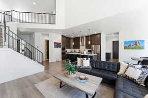 Spacious living area featuring high ceilings, LVP-finish flooring, and a contemporary open staircase with black metal railings