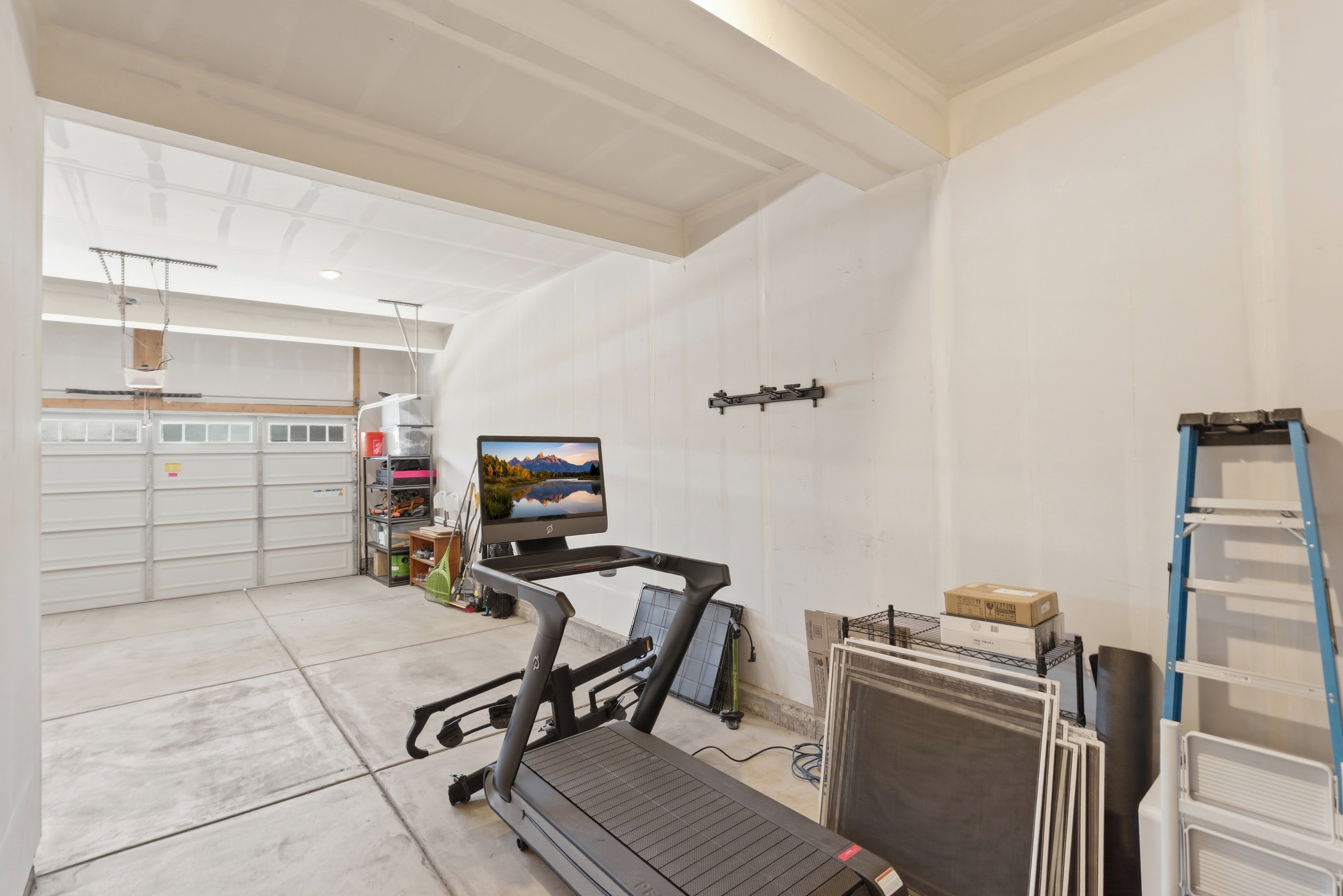 Spacious garage featuring a concrete floor, painted walls, and a two-car garage door with upper window panels