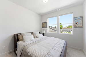 Bright bedroom featuring two large windows, neutral wall tones, and light-toned flooring