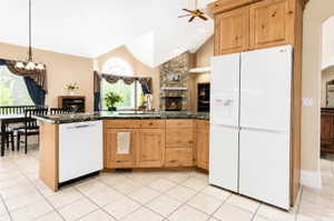 Kitchen featuring wood cabinetry, dark speckled countertops, and an integrated white dishwasher