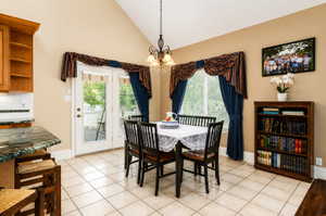 Dining area featuring vaulted ceilings, tile flooring, a built-in bookshelf, and French doors