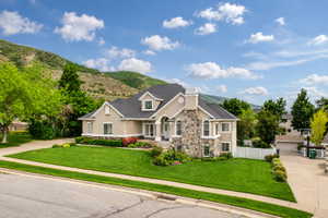 Stucco and stone exterior with dormer windows and a dark shingle roof