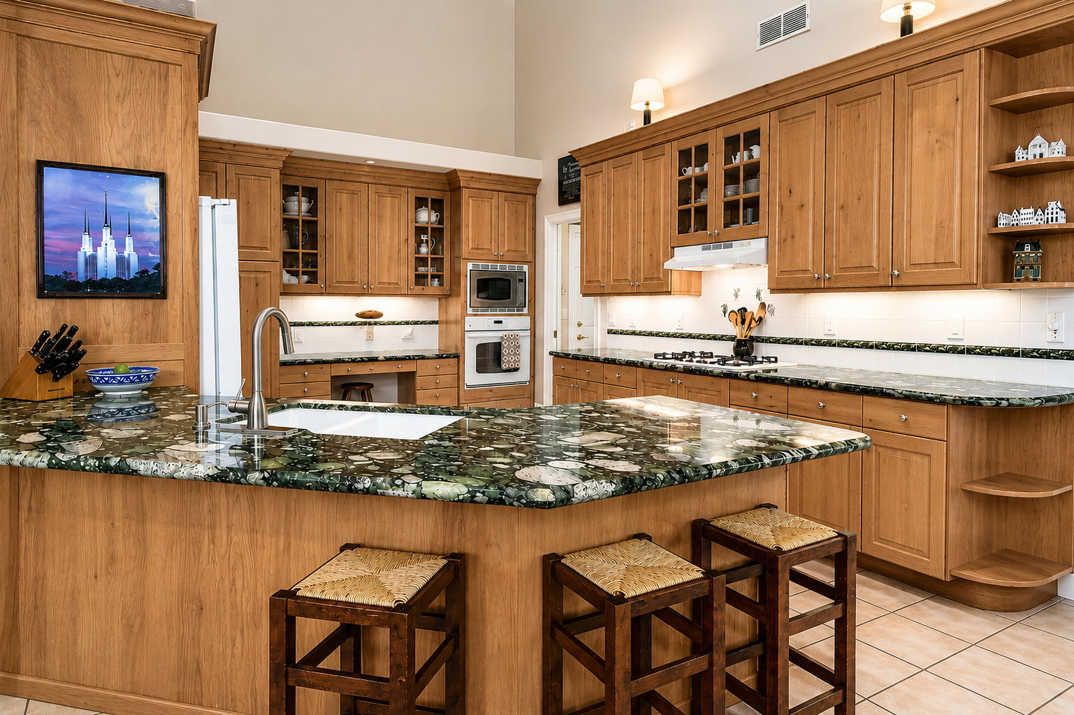 Kitchen featuring a central island with a built-in sink and granite-finish countertop, light wood cabinetry, white tile backsplash, and stainless steel appliances including a wall oven and microwave
