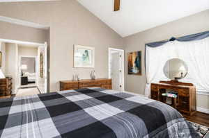 Vaulted ceiling bedroom with ceiling fan, wood-finish flooring, and natural light from a window with blinds