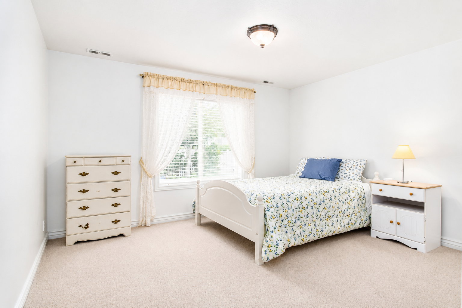 Bright bedroom with neutral wall paint and plush carpet flooring