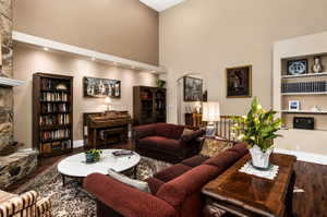 Spacious living area featuring a stone fireplace with a substantial hearth and mantel, high vaulted ceilings, recessed lighting, and rich wood-finish flooring