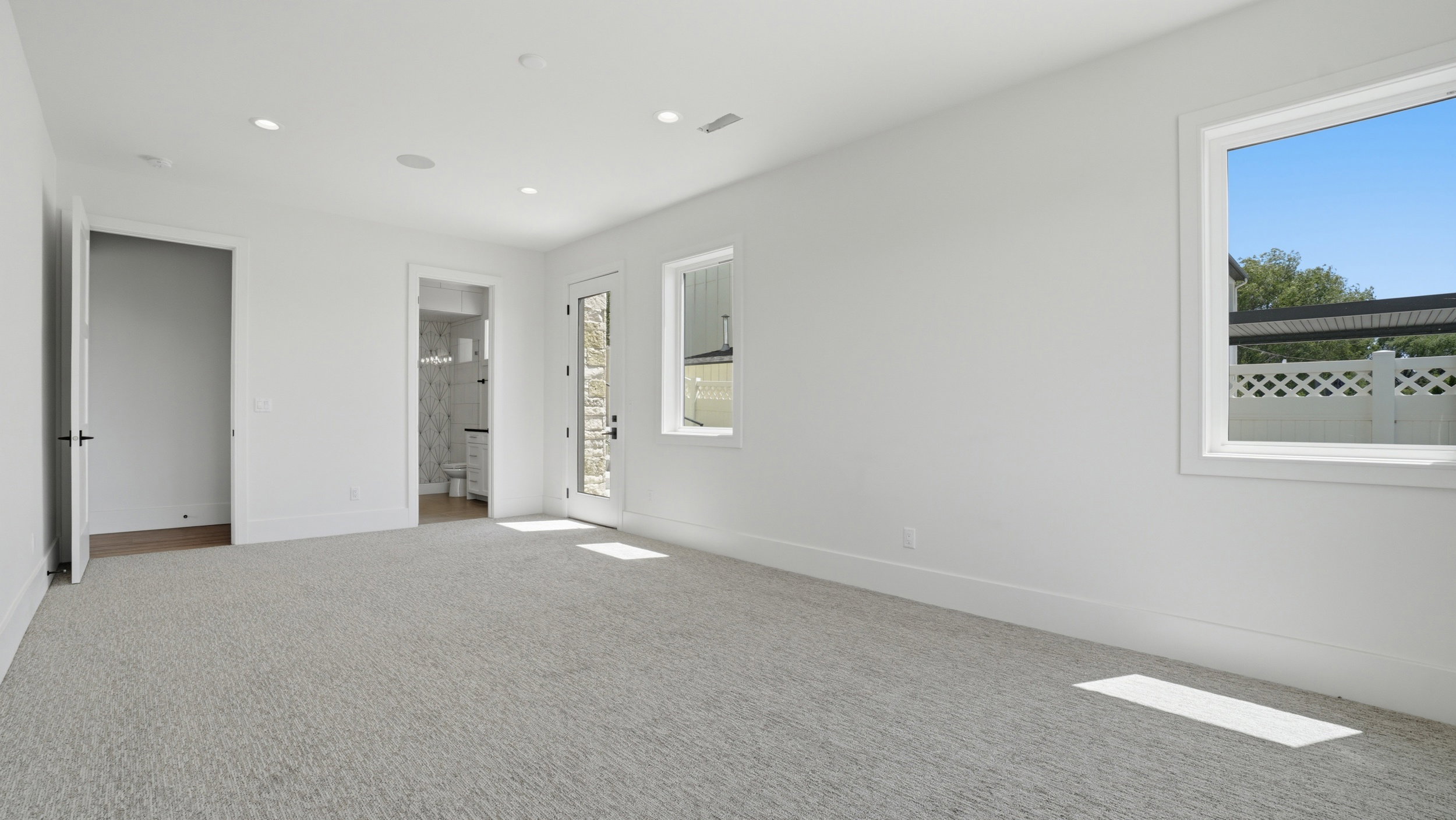 Spacious room with light-colored carpeting, white walls, and recessed lighting