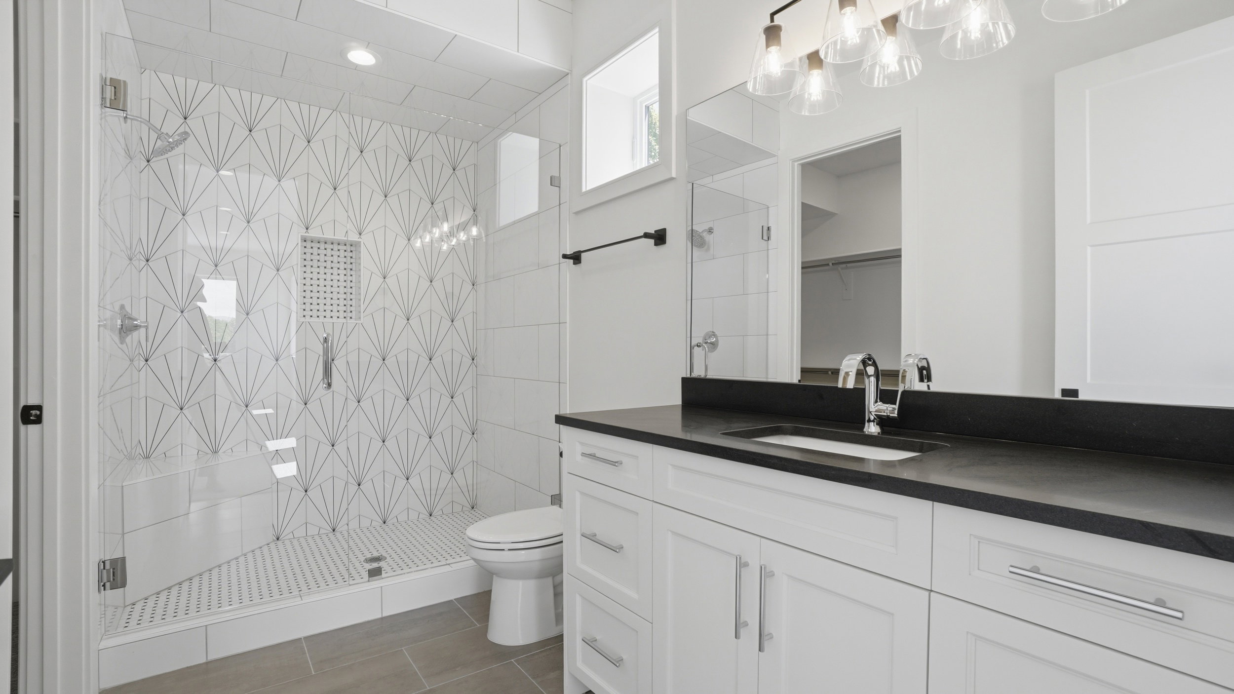 Contemporary bathroom featuring a spacious glass-enclosed shower with a decorative tiled accent wall and built-in niche
