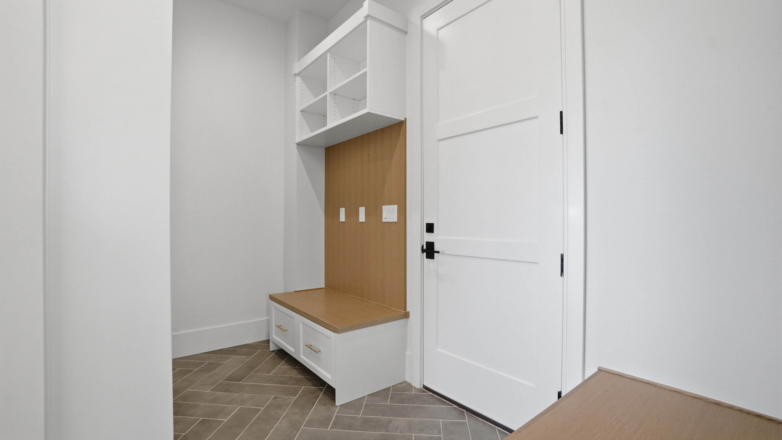 Built-in mudroom bench with natural wood-finish backing, upper cubbies, and lower cabinet storage