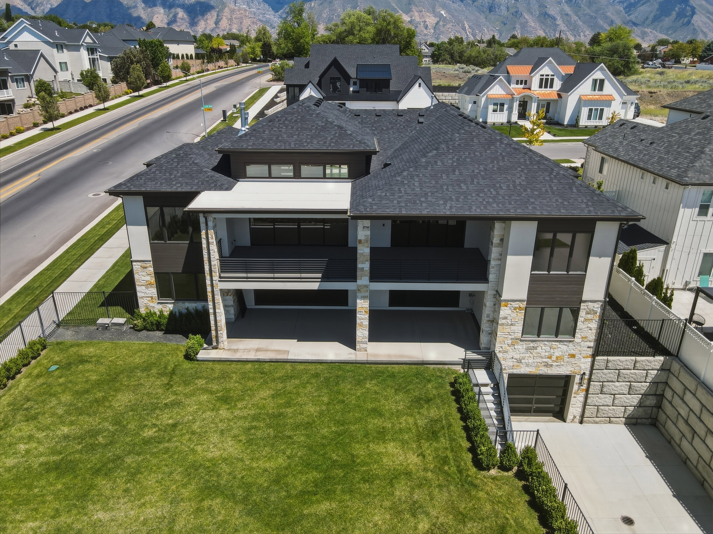 Contemporary multi-level residence featuring a dark shingle roof, stone and stucco facade, and multiple outdoor living areas