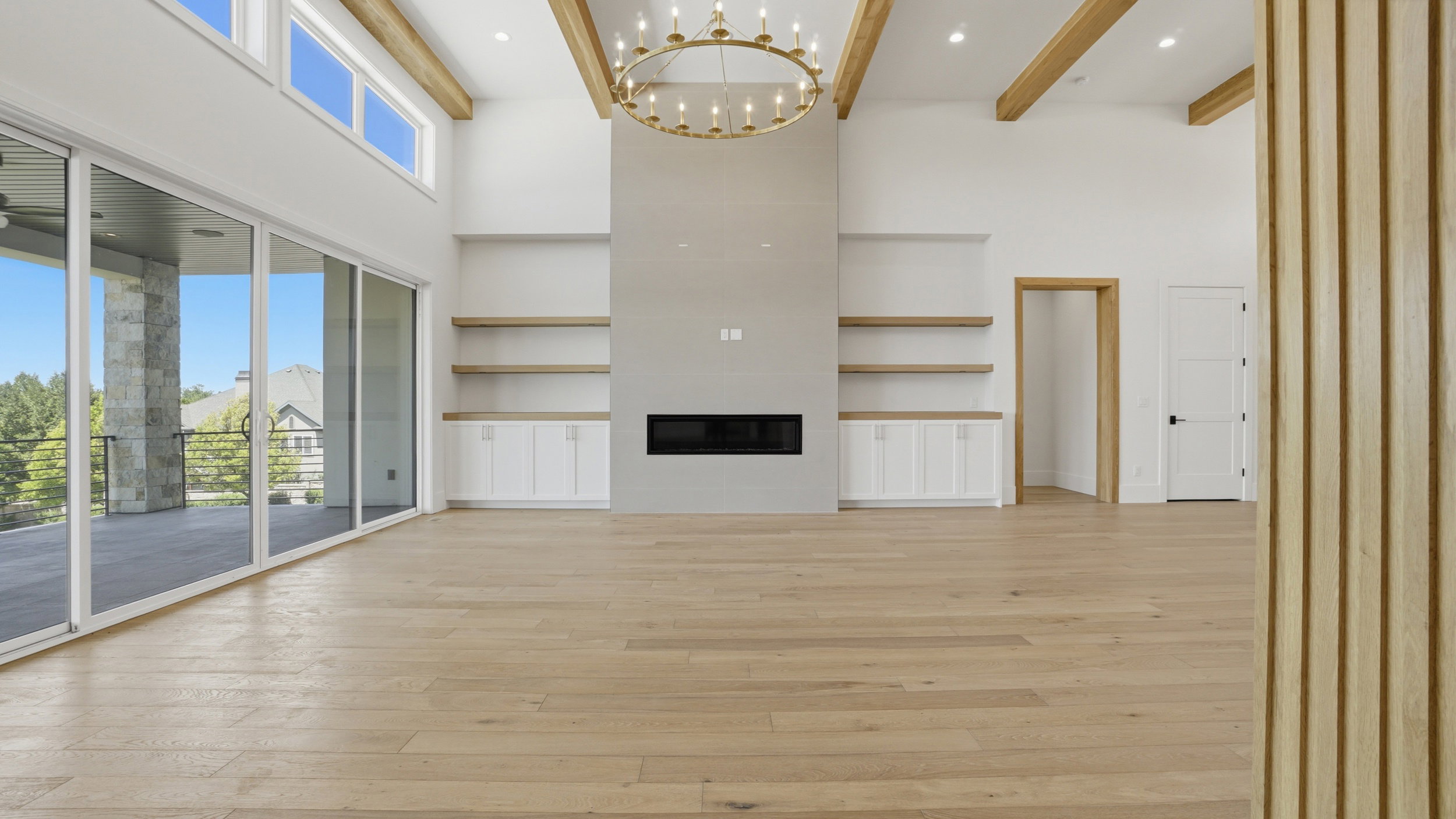 Spacious living area featuring light wood-finish flooring, a contemporary linear fireplace, and built-in shelving with lower cabinetry