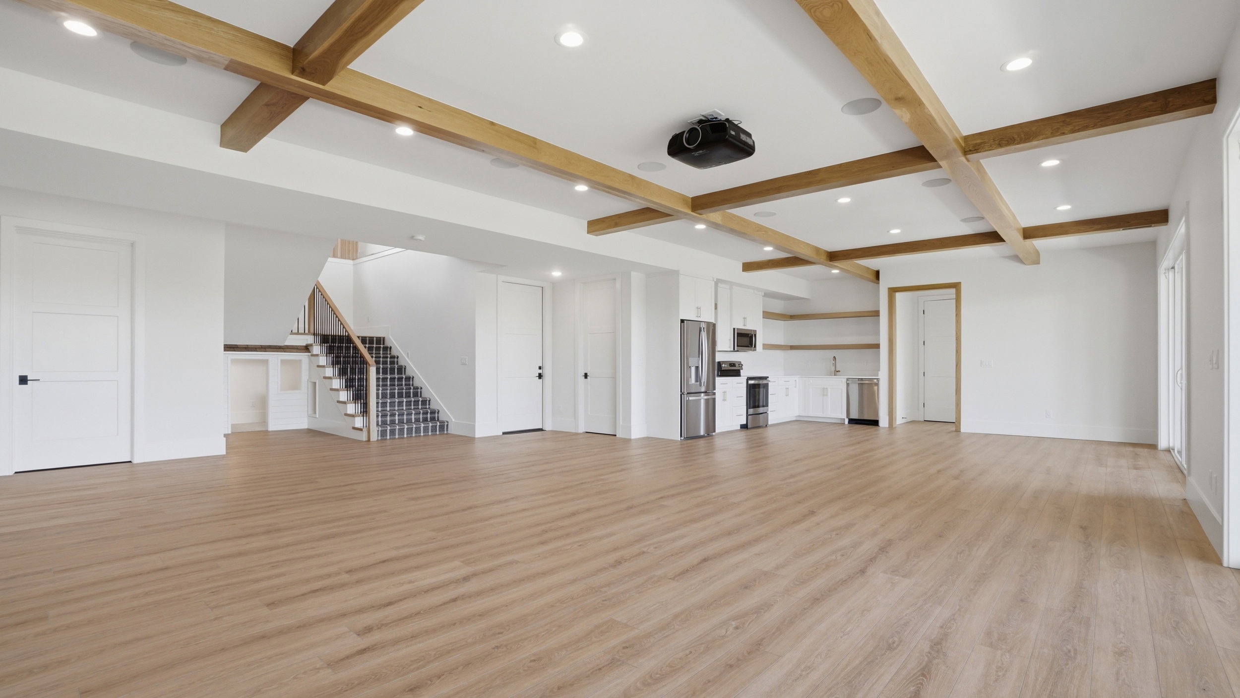 Expansive room with wood-finish flooring and a coffered ceiling featuring wood beams and recessed lighting