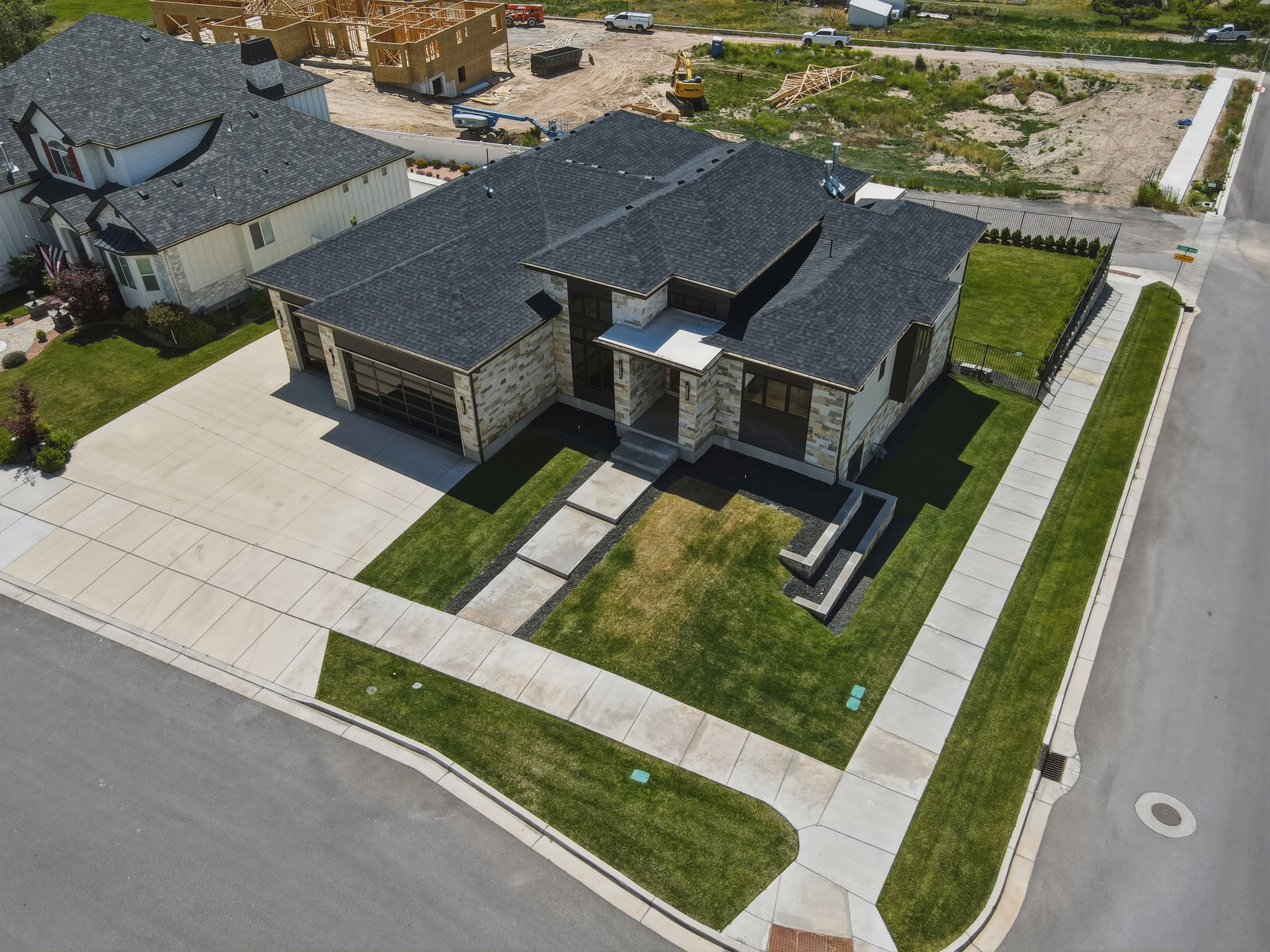 Modern home exterior featuring a stone and stucco facade, a dark shingle roof, and a concrete driveway