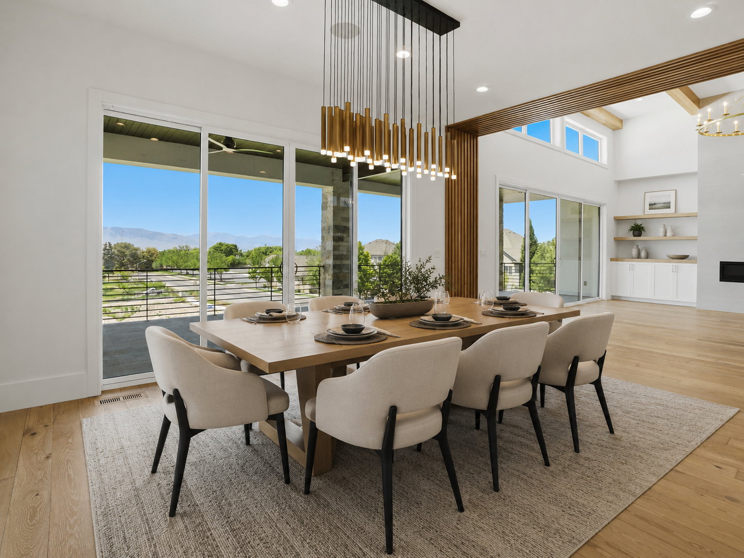 Spacious dining area featuring an expansive sliding glass door, contemporary linear chandelier, light wood-finish flooring, and a large wooden dining table AI Decor