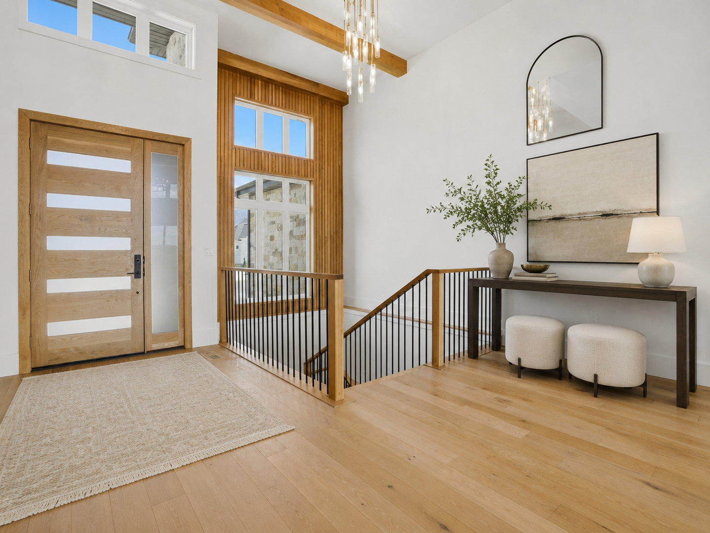 Two-story entry featuring light wood-finish flooring, a modern chandelier, and a wood-paneled accent wall