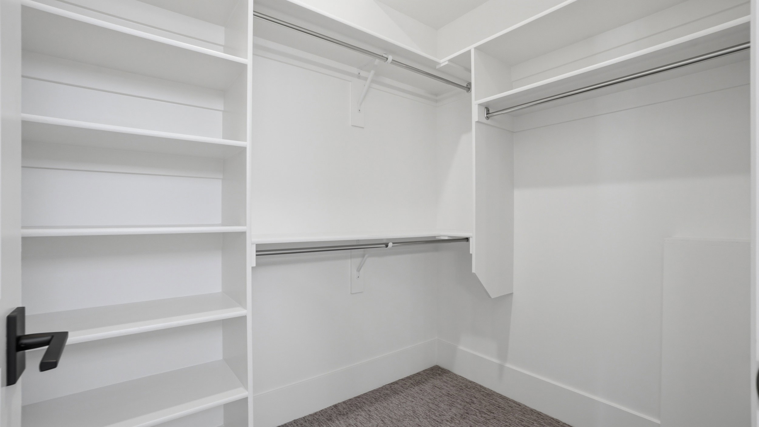 Walk-in closet featuring built-in shelving, multiple hanging rods, white trim, and carpet flooring
