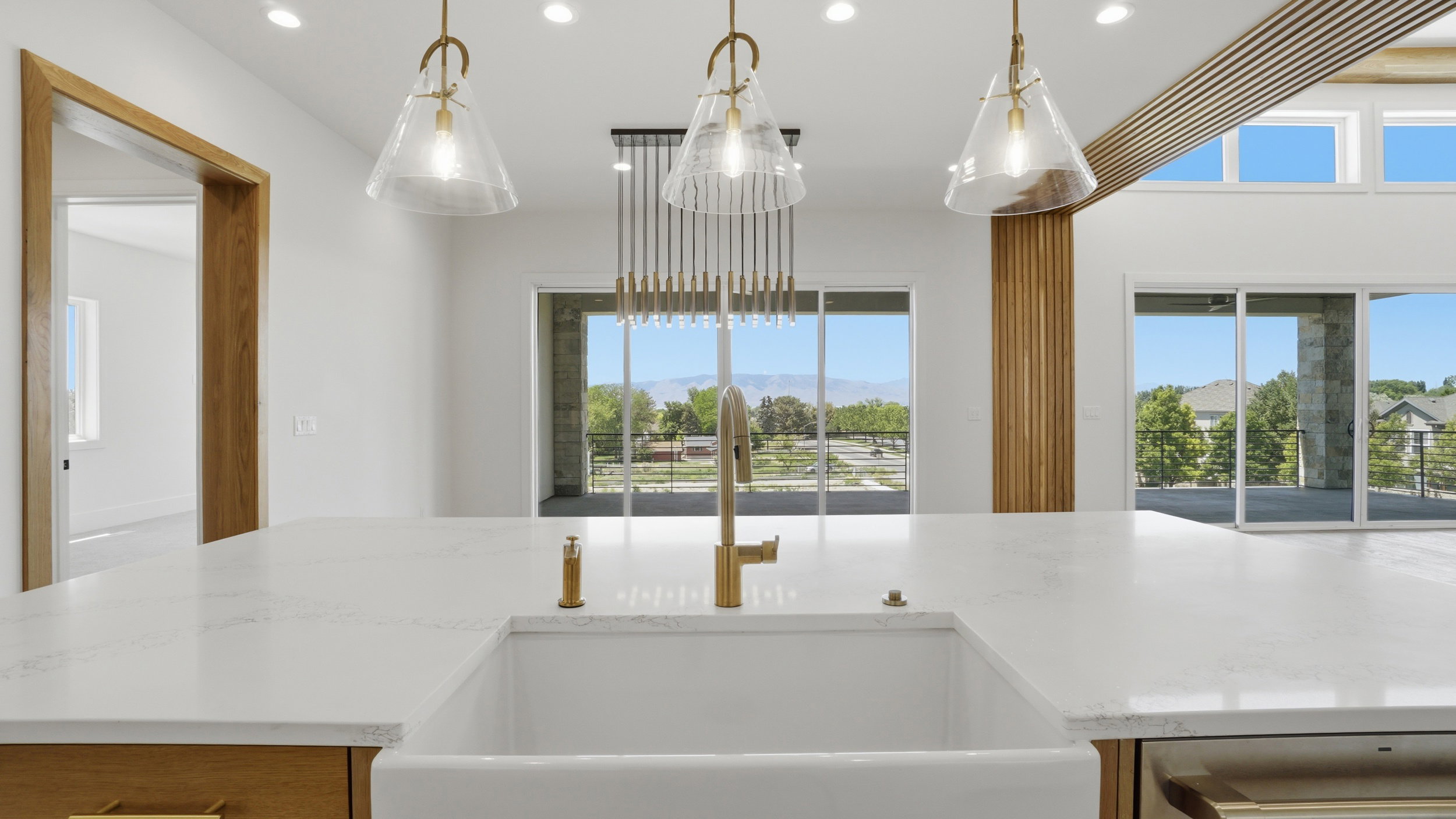 Expansive kitchen island featuring a farmhouse sink and brass faucet, complemented by three pendant lights