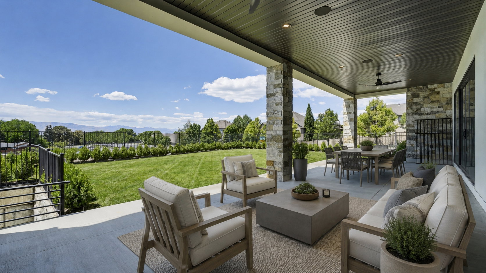 Expansive covered patio featuring stone-clad pillars, a dark paneled ceiling with recessed lighting and a ceiling fan, and a large dining area