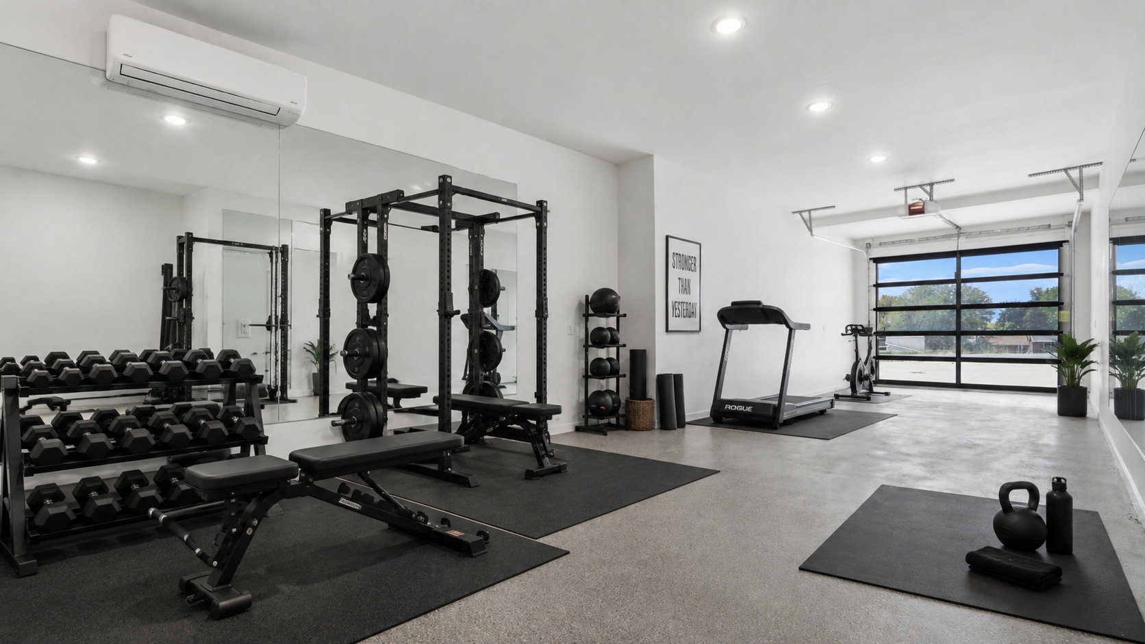 Dedicated fitness space featuring light-toned flooring, recessed lighting, and a full-view glass garage door AI gym option with flexspace