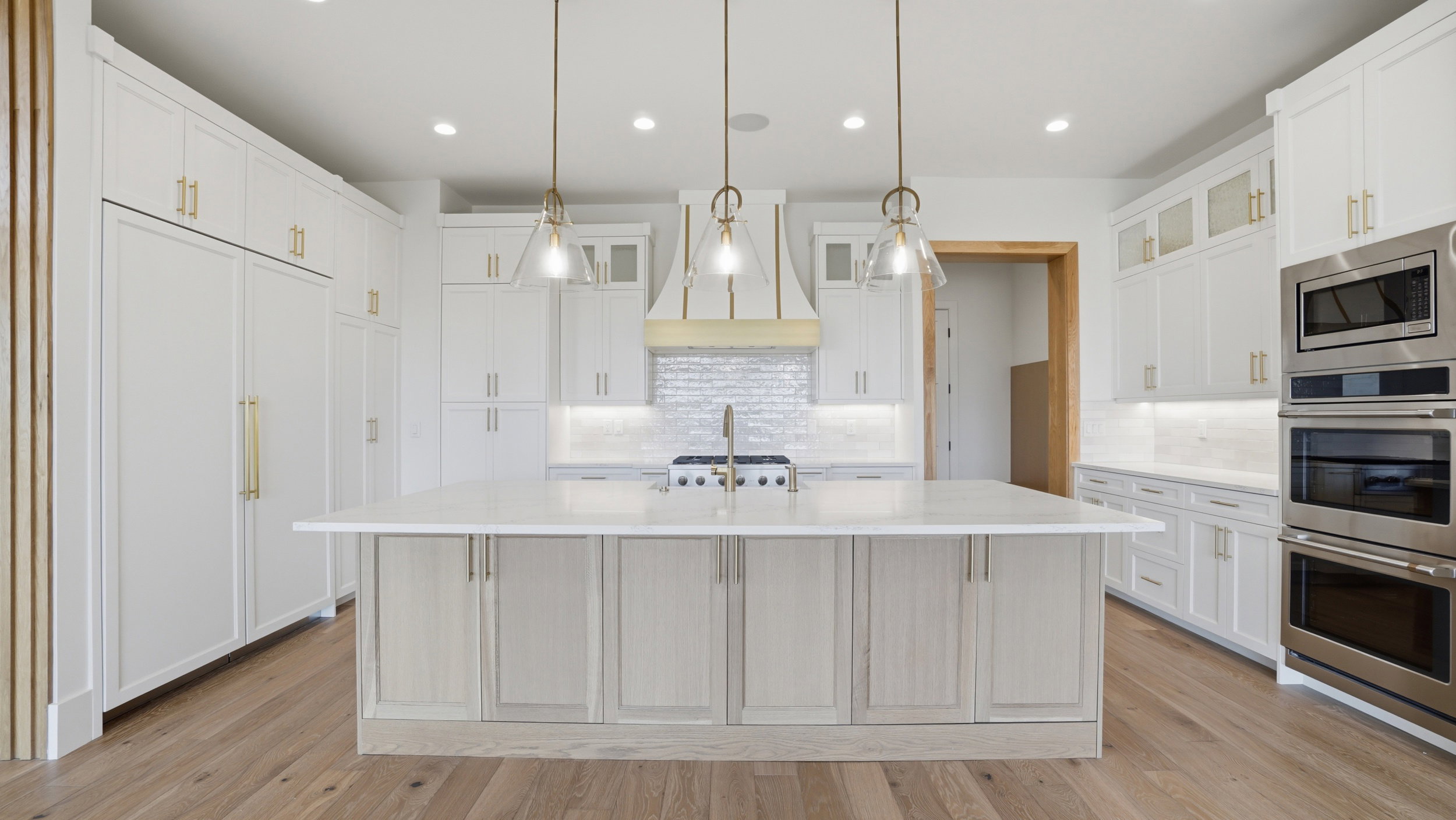 Gourmet kitchen featuring a large central island with light-toned cabinetry, white quartz countertops, and three pendant light fixtures