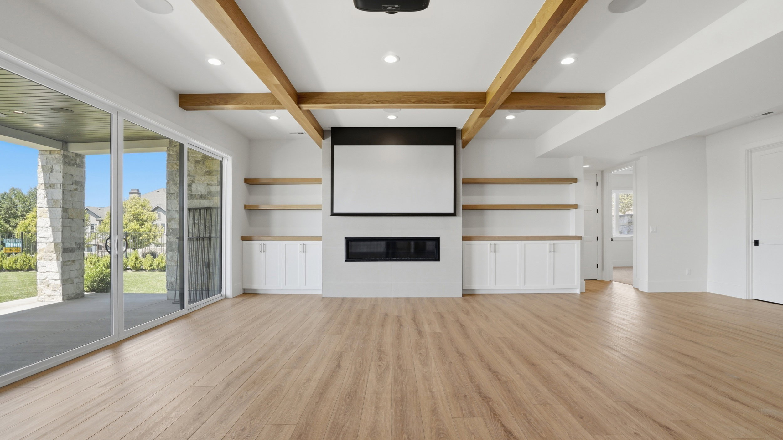 Spacious room featuring wood-finish flooring, exposed ceiling beams, and recessed lighting