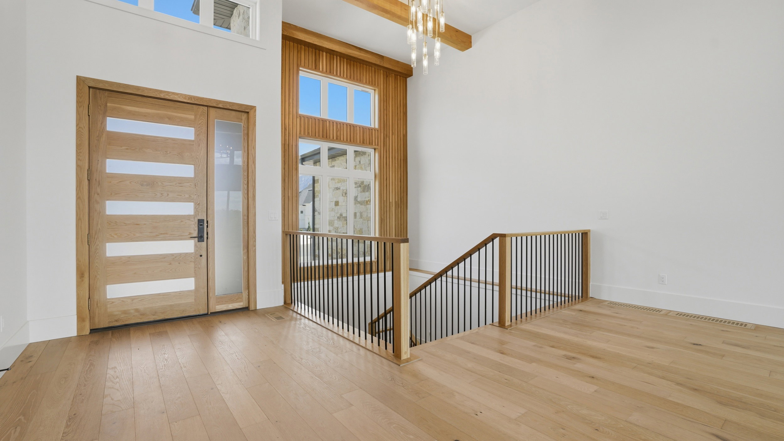 Entryway with light wood-finish flooring and a contemporary wood door featuring horizontal frosted glass panels