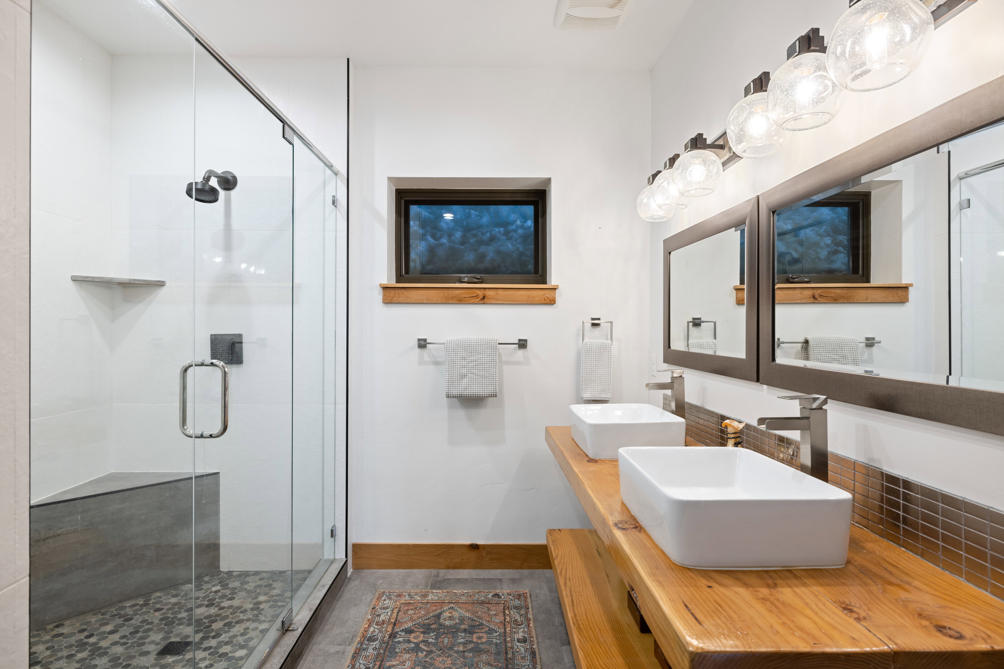 Full bath featuring a shower stall and double vanity