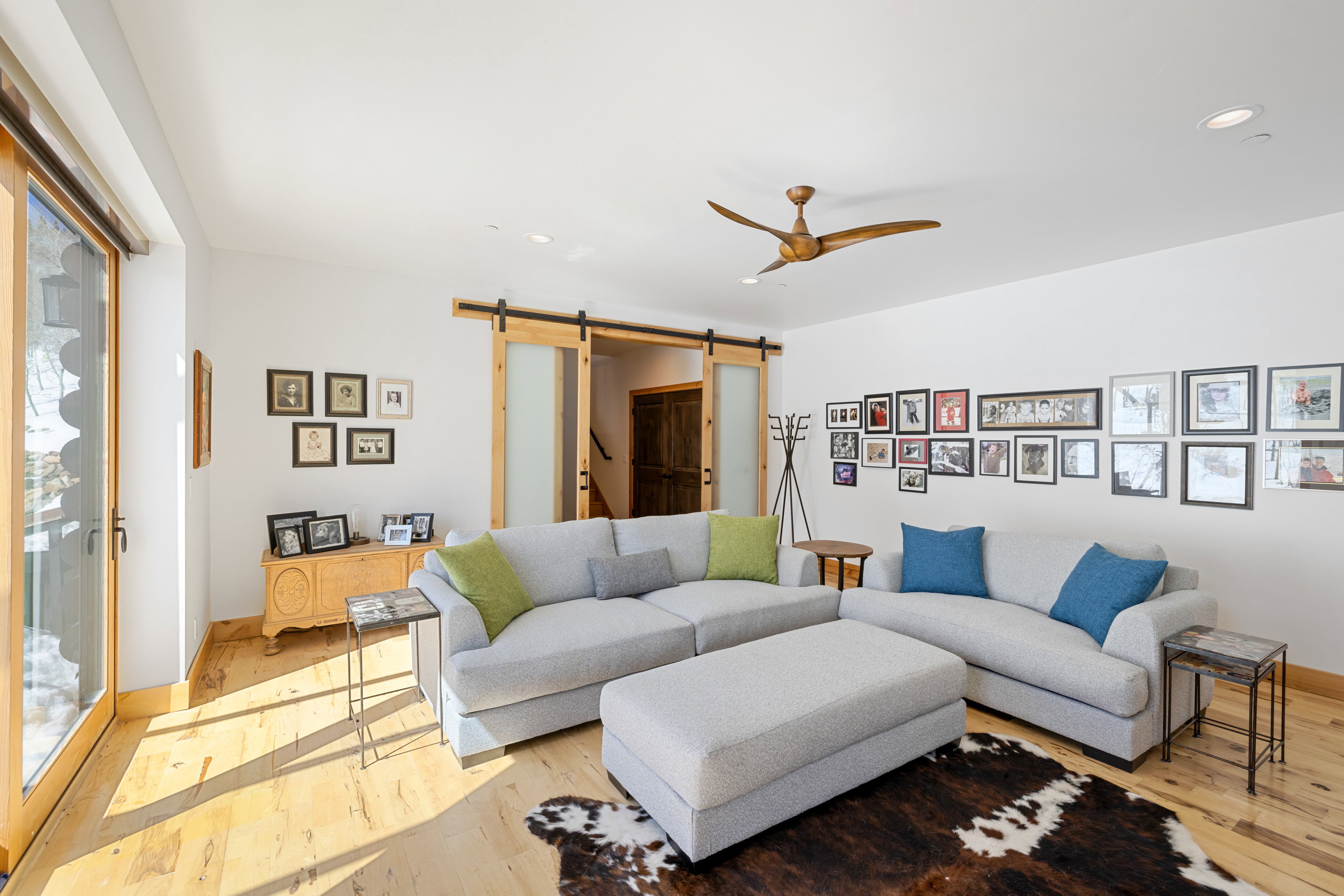 Living area featuring a barn door, ceiling fan, light wood finished floors, and recessed lighting