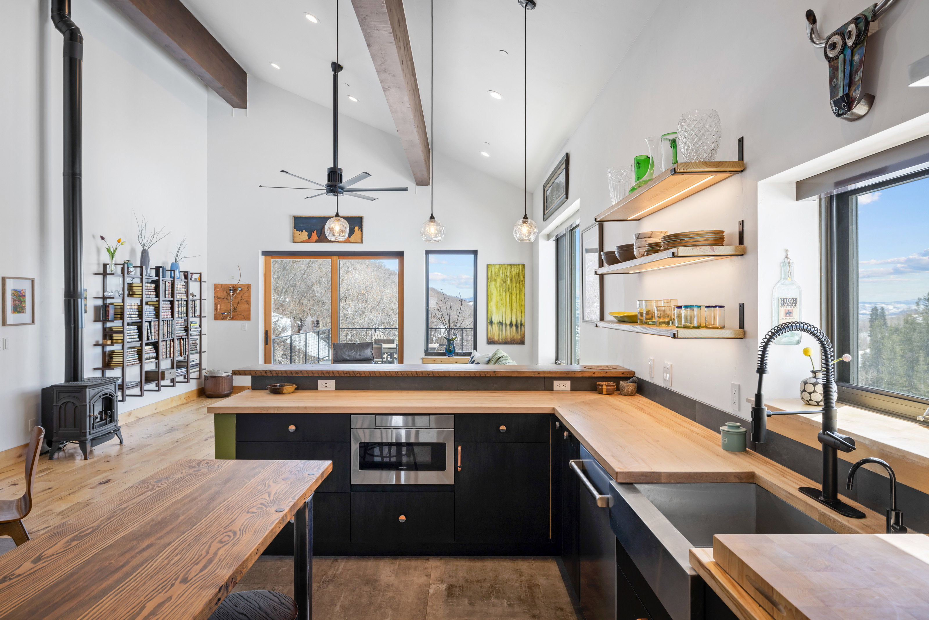 Kitchen with dark cabinets, wooden counters, open shelves, light wood-style flooring, and a peninsula