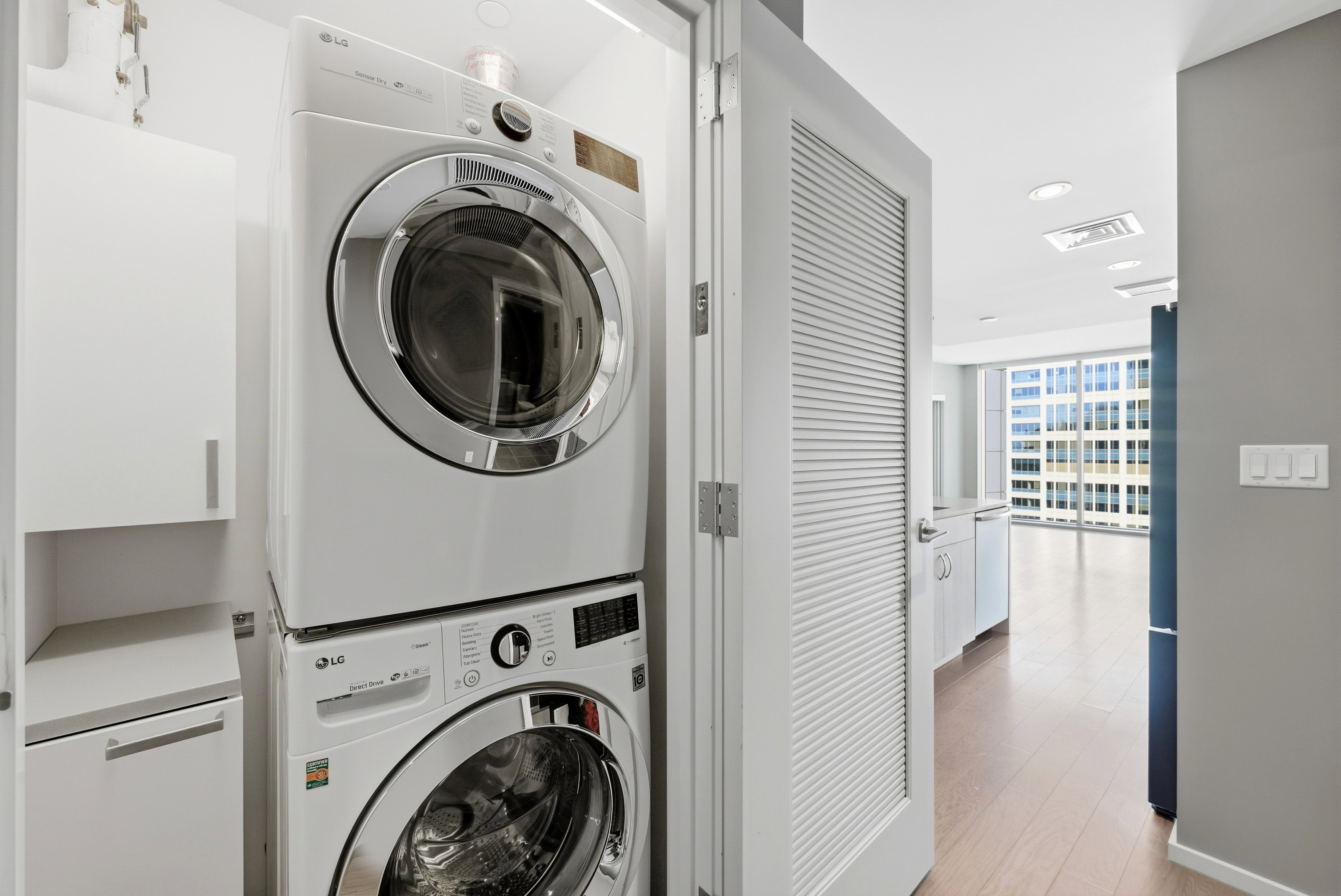 Dedicated laundry area featuring stacked front-load washer and dryer, white cabinetry, and light-toned countertop