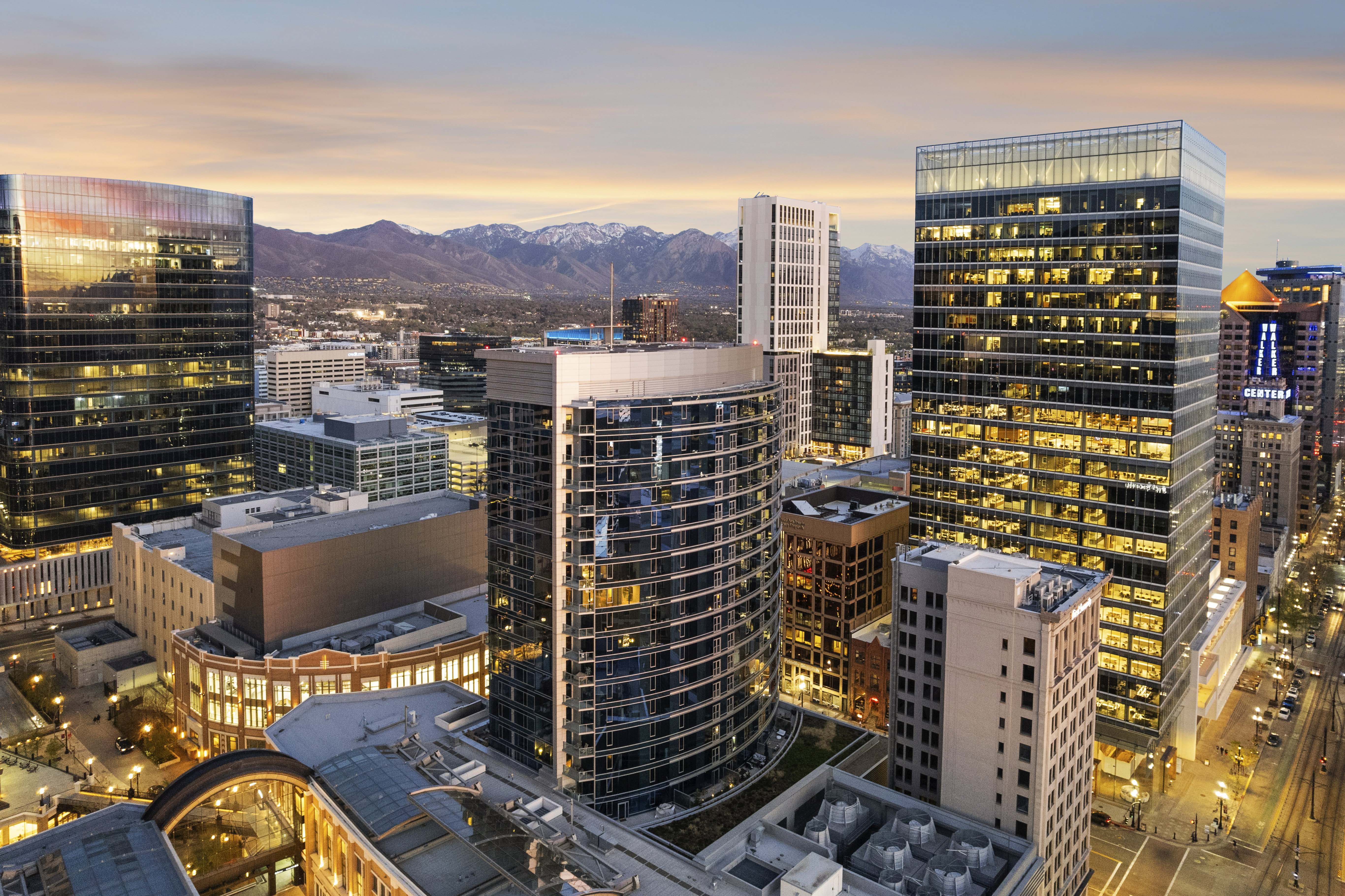 Urban skyline with modern high-rise buildings featuring glass facades and illuminated interiors