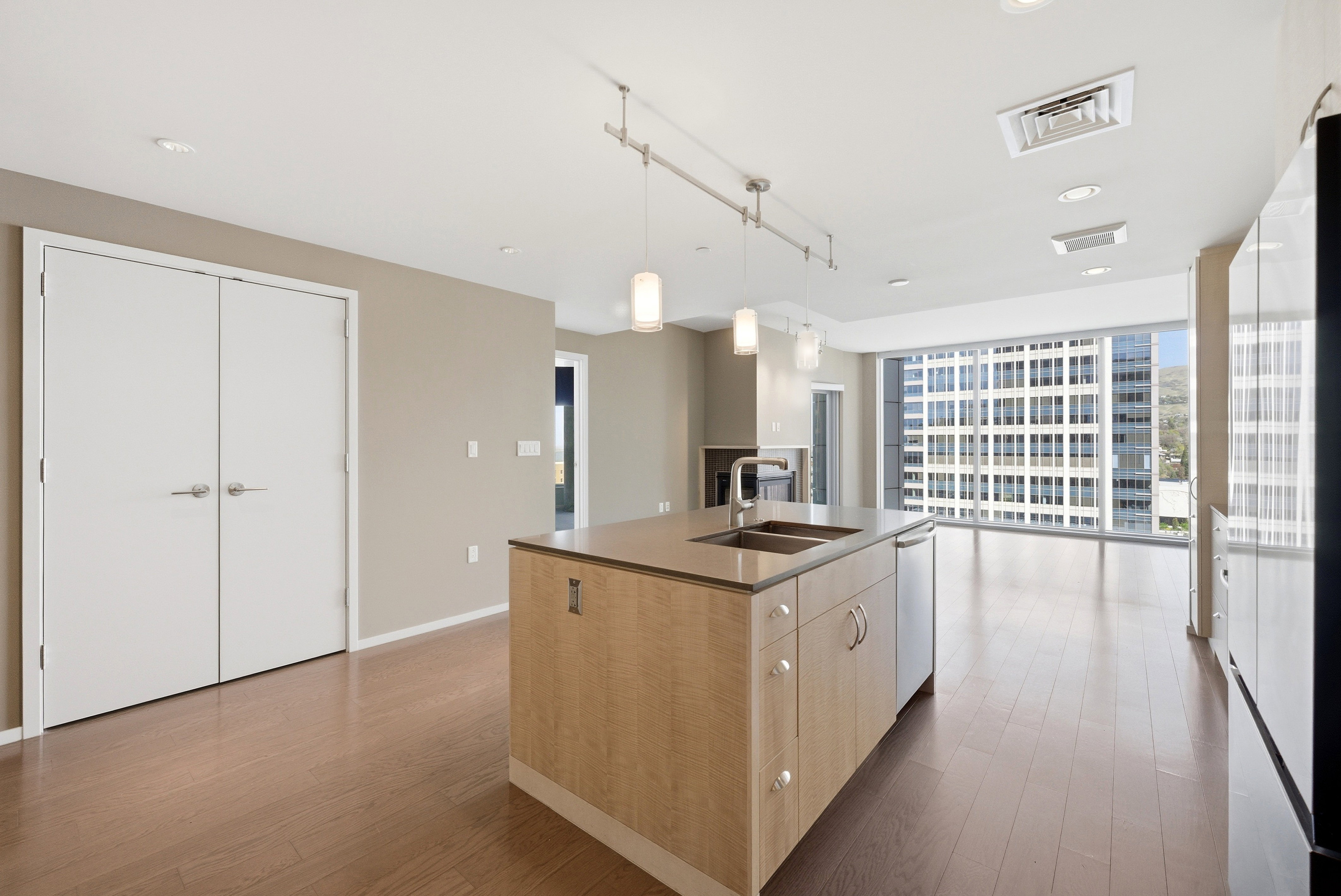 Modern kitchen island with integrated double-basin sink, pendant lighting, and stainless steel dishwasher