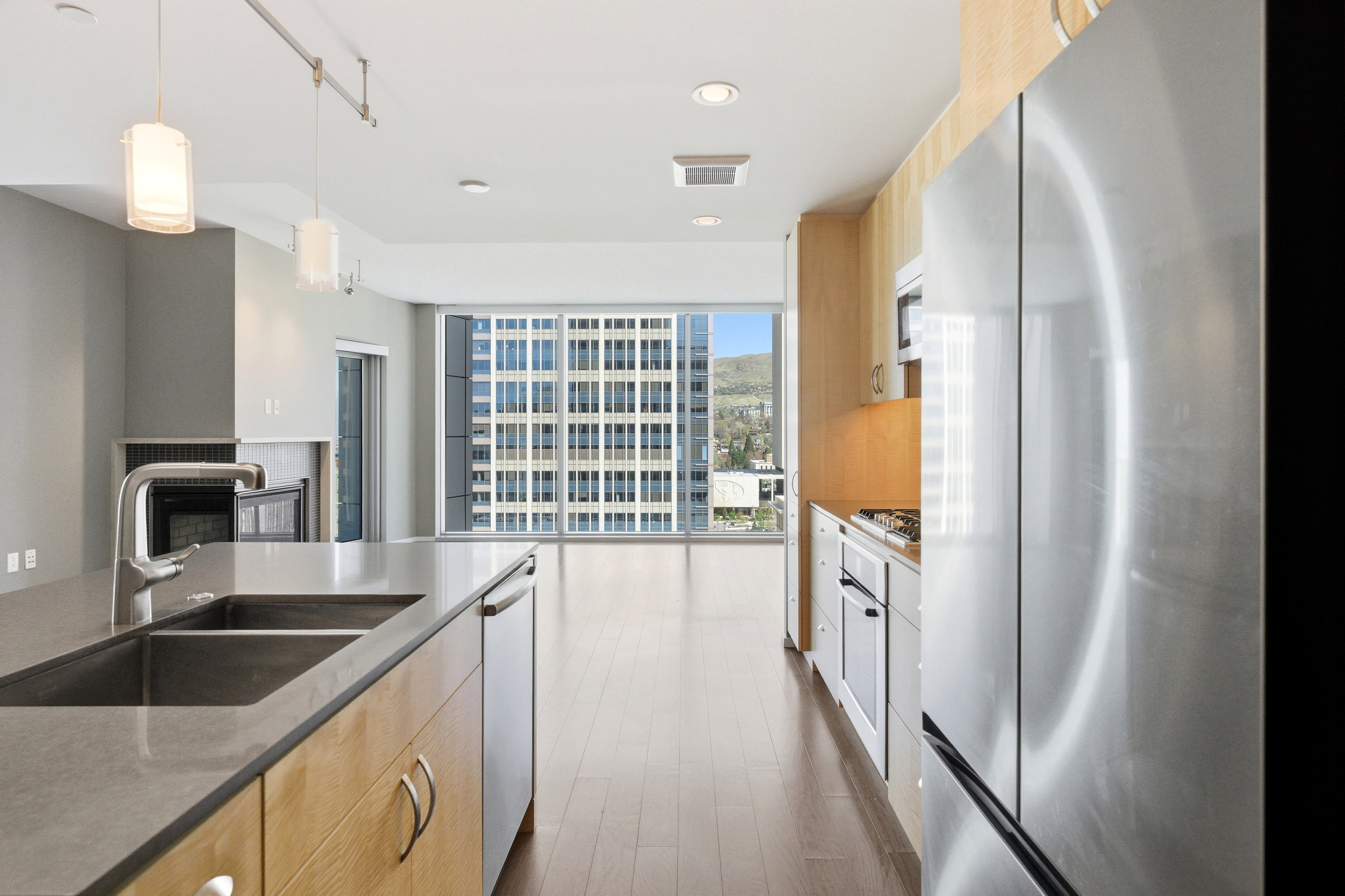 Modern kitchen featuring stainless steel appliances, wood-finish cabinetry, and a large center island with an undermount double sink