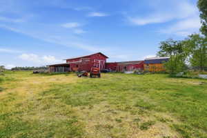 Expansive grassy field with multiple red barn structures and an additional yellow shed