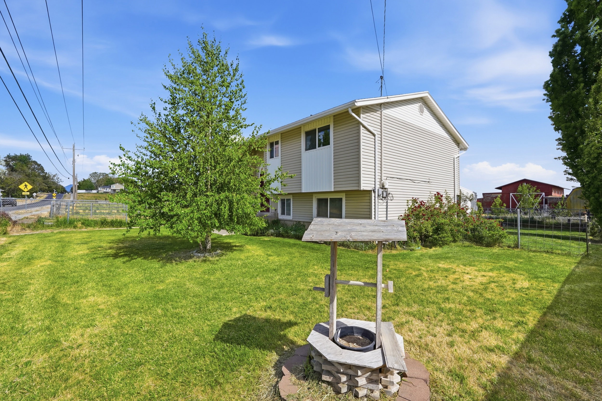 Expansive green lawn featuring a decorative wishing well with a stone base and a mature tree