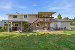 Expansive backyard featuring a large grassy area, a covered patio, and a second-story deck with wooden stairs